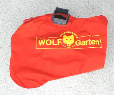 A red collection bag with a gray plastic attachment lies on a speckled gray and white surface.