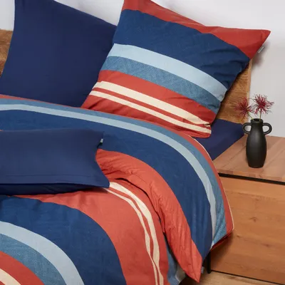 A close-up view of a striped duvet cover and pillow on a bed.