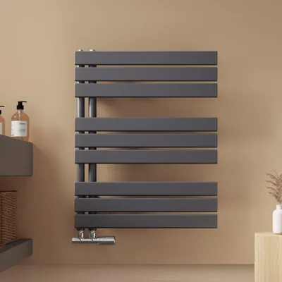 A modern bathroom setting with a dark gray towel radiator mounted on a light beige wall.
