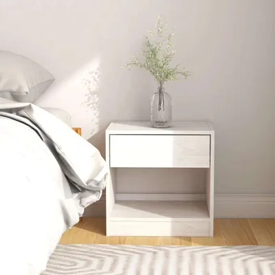 A white nightstand next to a bed with white bedding.