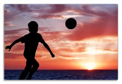 Produktbild von Wallario Frühstücksbrettchen aus Glas 20 x 30 cm mit rutschfesten Füßen, Motiv Fußball - Kleiner Junge spielt im Abendrot