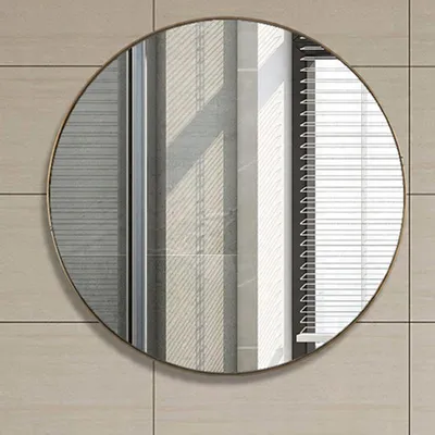 A round mirror with a gold frame is mounted on a tiled wall.