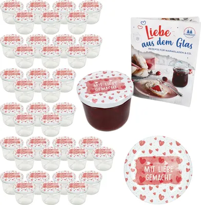 A set of glass jars with lids, a recipe book, and a loose lid, all decorated with hearts and the phrase 'Mit Liebe gemacht'.