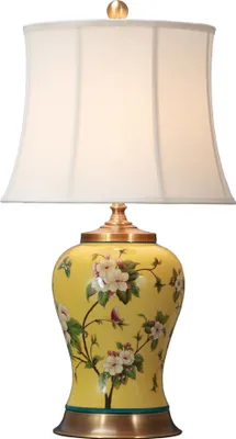 A yellow ceramic table lamp with a floral pattern and a white lampshade.
