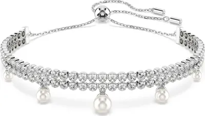 A close-up studio shot of a silver bracelet with pearls and crystals.