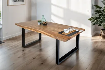A dining table in a well-lit room with wooden floors and a large plant.