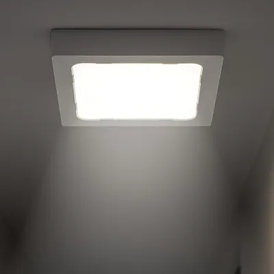 A square LED panel light mounted on a ceiling, emitting a bright white light downwards.