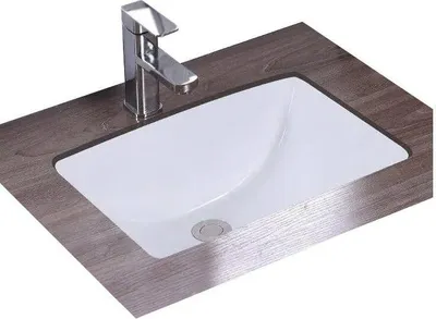 A white rectangular sink with a chrome faucet is set into a dark wood-grain countertop.