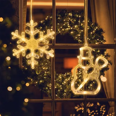Christmas decorations hanging in a window at night.