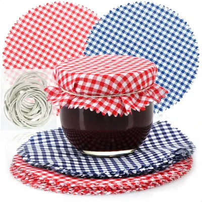A jar of jam is decorated with a red and white checkered fabric lid and surrounded by matching fabric circles and white elastic bands.