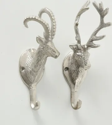 Two silver-colored decorative wall hooks, shaped like deer heads with antlers, are shown against a white background.
