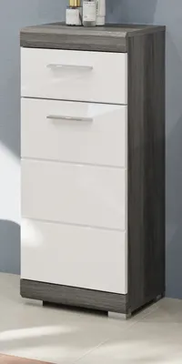 A tall, narrow chest of drawers with a gray wood-grain top and sides, and white high-gloss drawer fronts. It is shown against a blue wall with light reflecting on the floor.