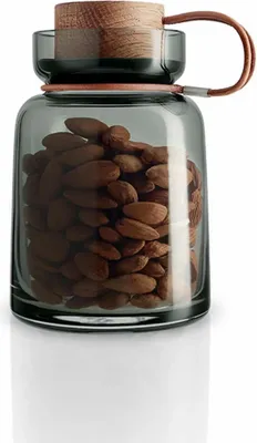 A glass storage jar filled with almonds, with a wooden lid and a leather strap.