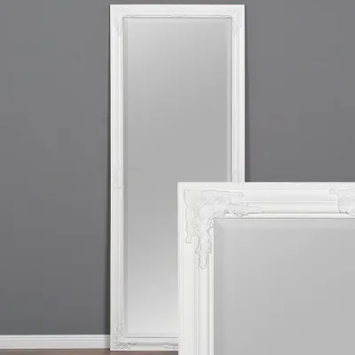 A full-length mirror with a white baroque frame stands against a gray wall.