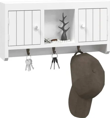 A white wall-mounted key cabinet with two doors and an open shelf in the middle. Hooks are attached below the shelf, holding keys and a brown cap.
