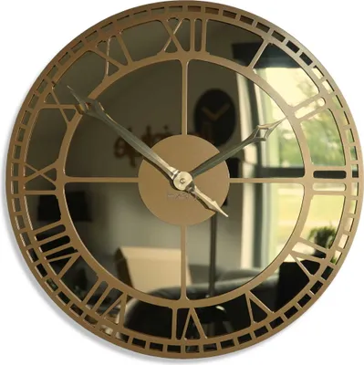 A large, round, gold-colored metal wall clock with a mirrored face and Roman numerals.