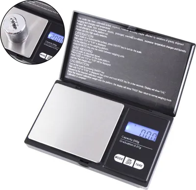 A black digital scale with a silver weighing platform is shown, with instructions visible on the inside of the lid. An inset shows a weight placed on the platform.