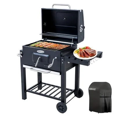 A black charcoal grill with the lid open, showing food cooking on the grates. A plate of cooked steak and vegetables is on a side table. A grill cover is shown separately.