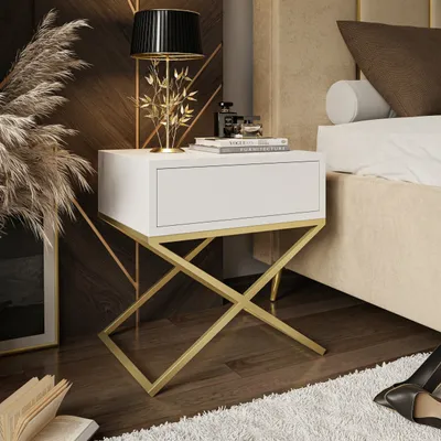 A modern bedroom setting with a white and gold nightstand next to a bed.