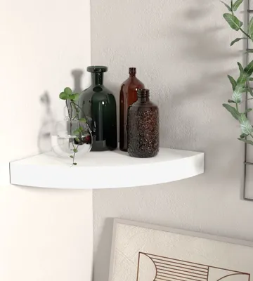 A white corner shelf with decorative bottles on it.
