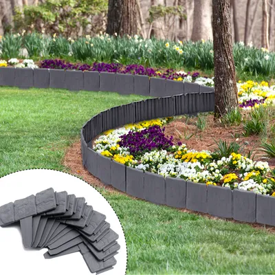 A garden landscape with a curved border made of gray plastic pieces, separating a grassy lawn from a flower bed with various colorful flowers.
