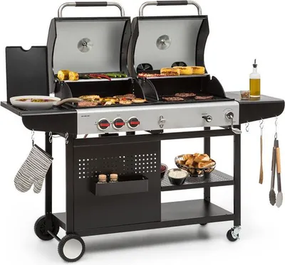 A dual-chamber gas and charcoal grill with food on the grates and side shelves.