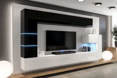 A modern living room wall unit with a television, shelves, and LED lighting.