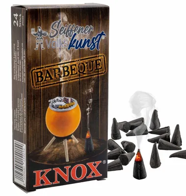 Auf dem Bild ist eine Verpackung von Räucherkerzen der Marke Knox zu sehen die für Barbecue-Duft sorgen und daneben liegen einige der kegelförmigen Räucherkerzen während eine davon raucht.