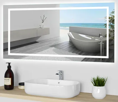 A modern bathroom with a large illuminated mirror reflecting a bathtub and the ocean.