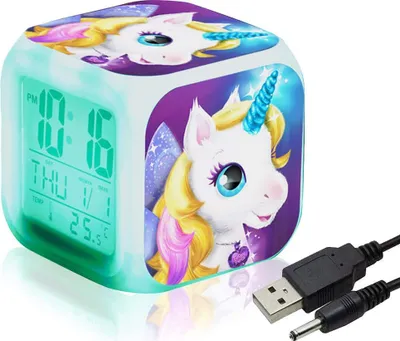 A cube-shaped digital alarm clock with a unicorn design, displaying the time, day, and temperature on its LCD screen. It is shown with a USB cable.