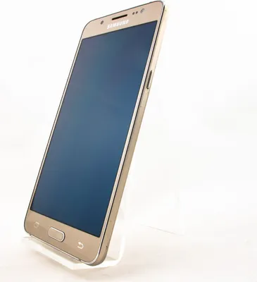 A gold Samsung Galaxy J3 smartphone is displayed on a clear stand against a white background.