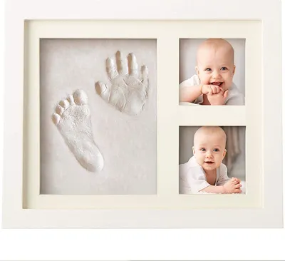 A baby handprint and footprint cast in a white wooden frame with two photos of a baby.