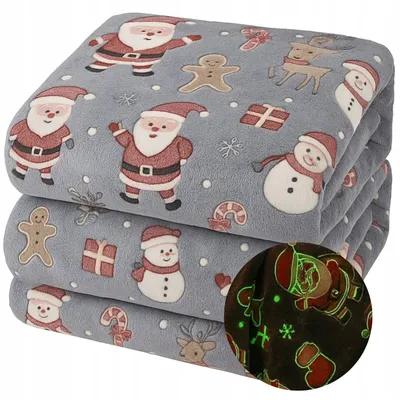 A stack of folded blankets with a Christmas theme, featuring Santa Claus, snowmen, gingerbread men, and reindeer.