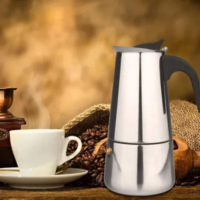 A coffee maker and a cup of coffee are displayed with coffee beans.