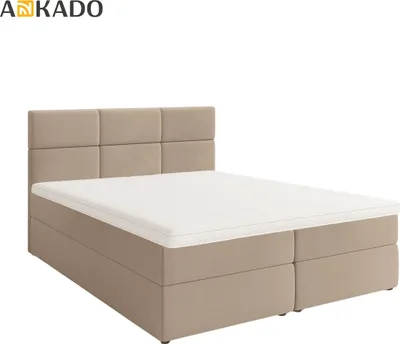 A studio shot of a beige boxspring bed with a headboard and mattress.