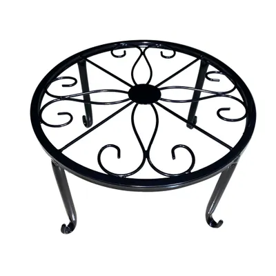A black metal plant stand with an ornate, circular top and three curved legs.