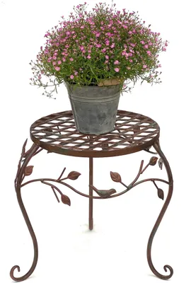 A potted plant with pink flowers sits on a decorative metal plant stand.