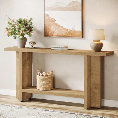 A wooden console table with a shelf, decorated with a vase of flowers, books, a decorative object, and a lamp. A woven basket is placed on the shelf.