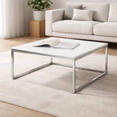 A modern living room with a white coffee table in the foreground and a sofa in the background.