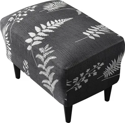A dark gray ottoman with a white fern leaf pattern, resting on four black legs, against a white background.