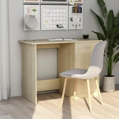 A desk and chair set up in a room with a plant and wall decorations.