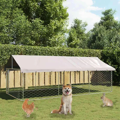A large outdoor dog kennel with a white roof, set up in a grassy yard with trees and a fence in the background. A dog, a chicken, and a rabbit are in front of the kennel.