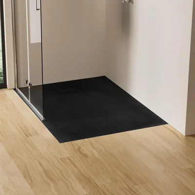 A black shower tray is installed in a bathroom with a glass shower enclosure and light wood flooring.