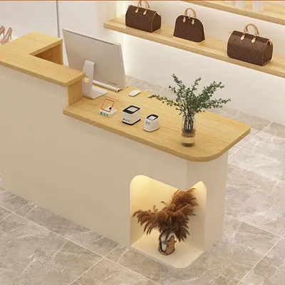 A retail counter with a computer, payment devices, and decorative plants.