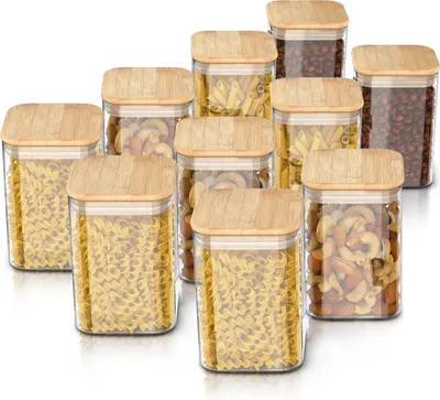 A collection of glass storage jars with bamboo lids, filled with various types of pasta and nuts.