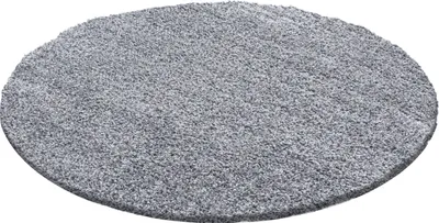 A round, high-pile rug is shown from a slightly elevated, diagonal angle against a white background.
