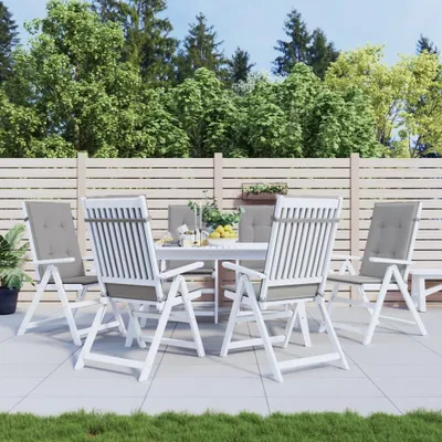 A patio set with chairs and a table in an outdoor setting with a wooden fence and trees in the background.