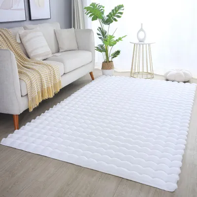 A white rug is placed in a living room setting next to a sofa.
