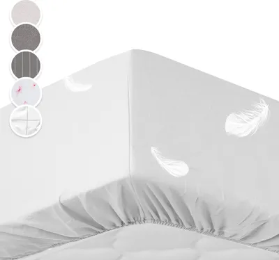 A white fitted sheet with a feather pattern is shown on a bed.