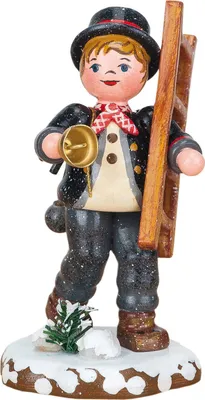 A wooden figurine of a chimney sweep standing on a snowy base.